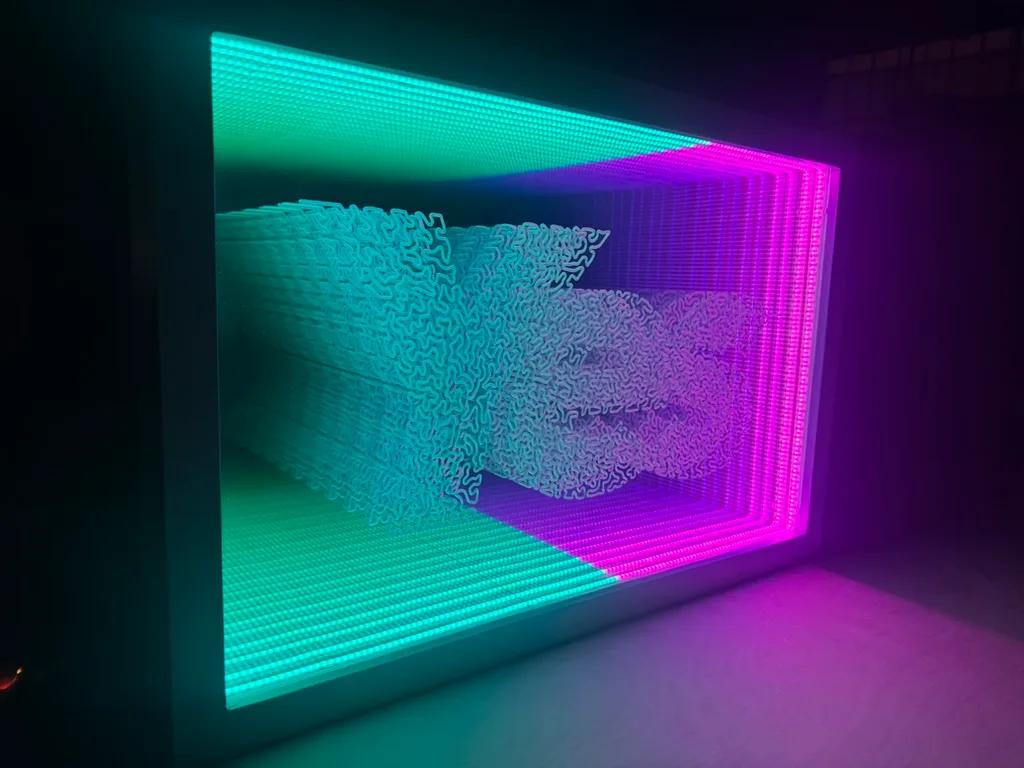 Daniel Dugan's infinity-mirror light box, fabricated by Fanfare: teal and magenta LED grid receding around sculpted script lettering